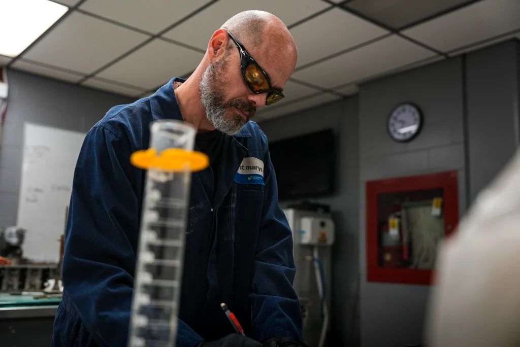 Bowmanville Cement Plant - lab technician in safety glasses working with a graduated cylinder in the Bowmanville quality lab