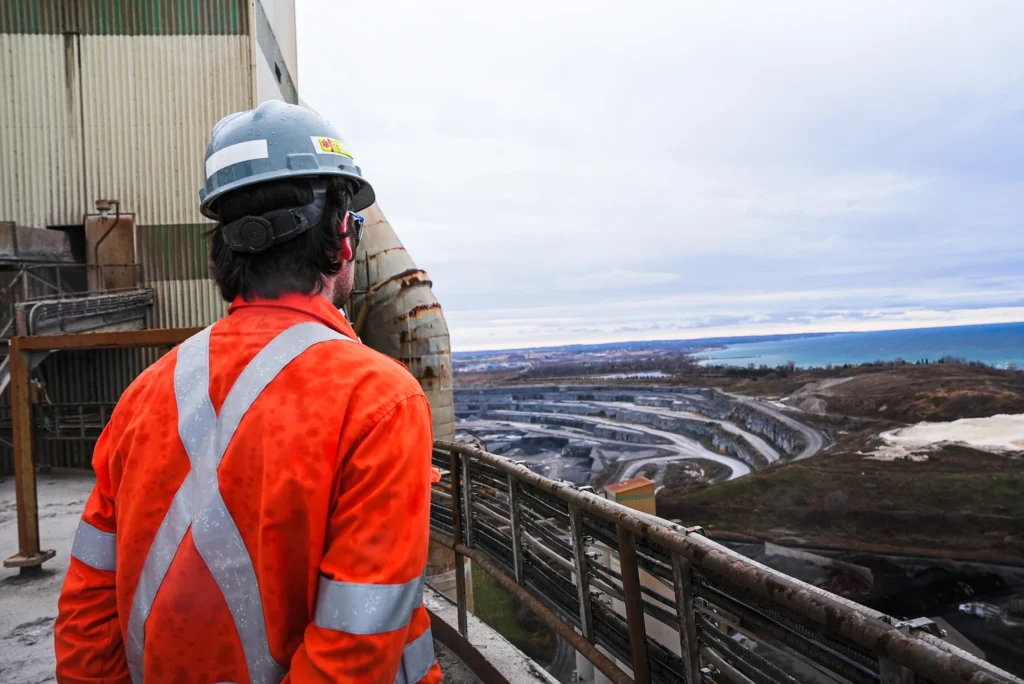 Cement Sustainability Commitments - team member in orange coveralls overlooking the Bowmanville quarry and Lake Ontario