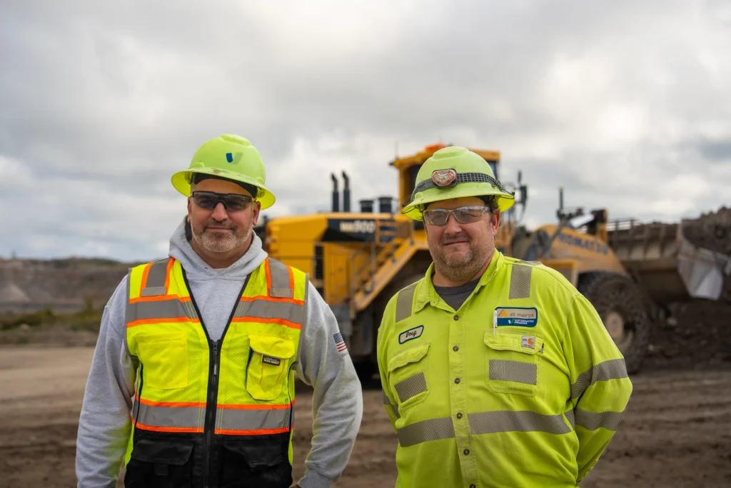 Charlevoix Cement Plant - two Charlevoix quarry team members in hi-vis gear standing in front of a loader