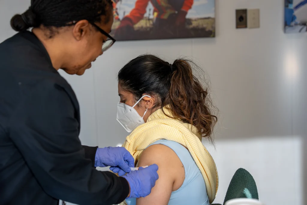 Cement Jobs - nurse giving a masked employee a vaccine at an on-site wellness clinic