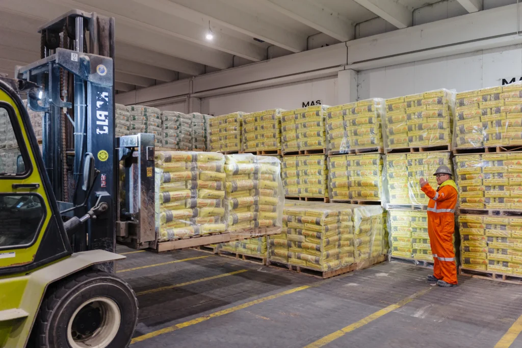 St Marys Community Relations - forklift moving pallets of bagged cement in the warehouse as a team member checks stock