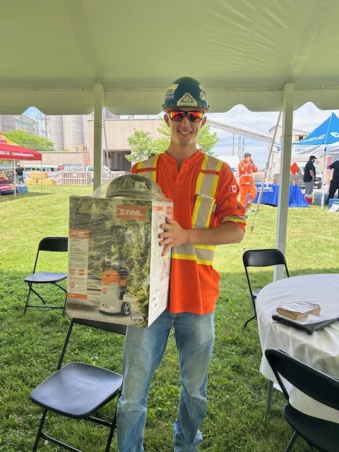 Safety in the Cement Industry - smiling worker in hi-vis holding a boxed STIHL prize under a tent at a safety day event