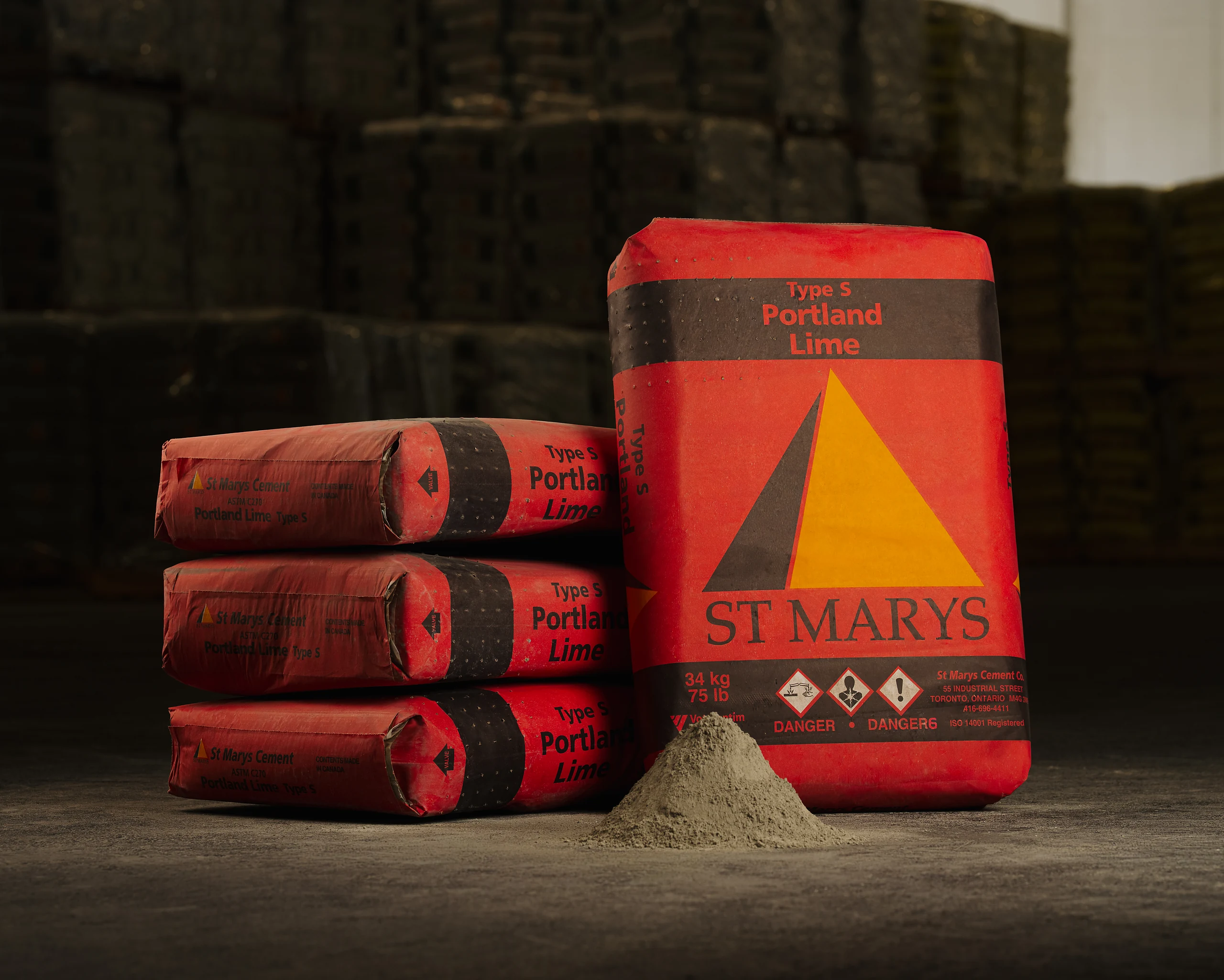 Red St Marys Type S Portland Lime bags stacked in a warehouse with a cone of grey powder