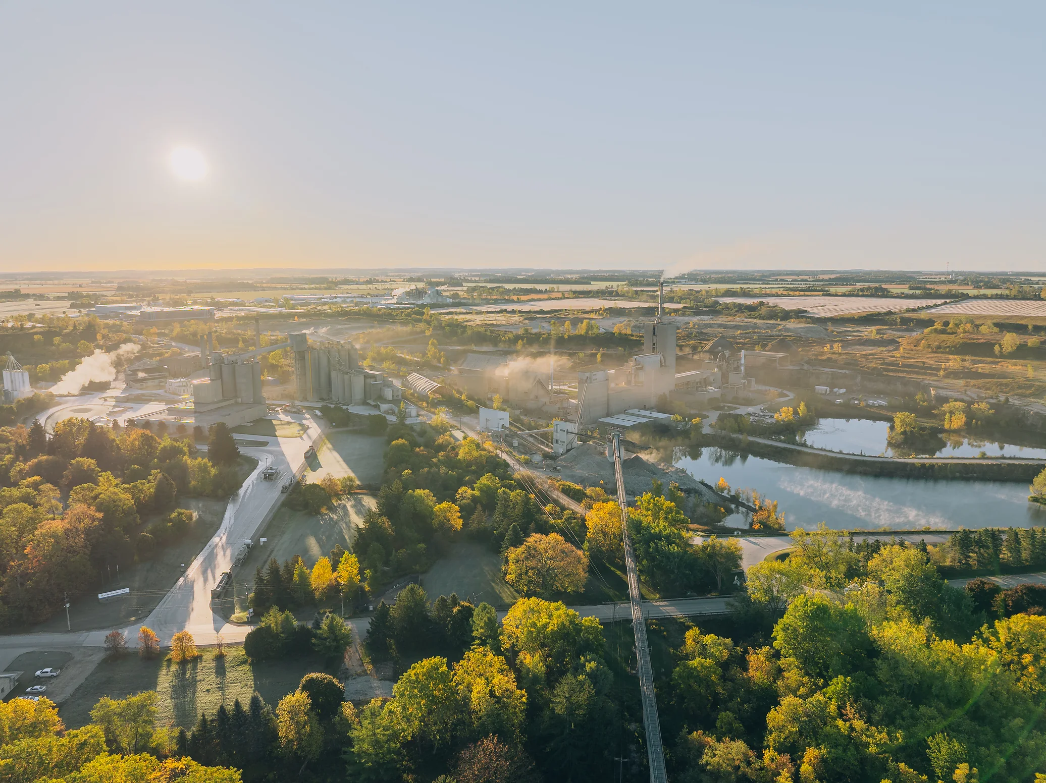 Type N Mortar Cement - morning aerial view over the cement plant, river and autumn trees with the sun low on the horizon