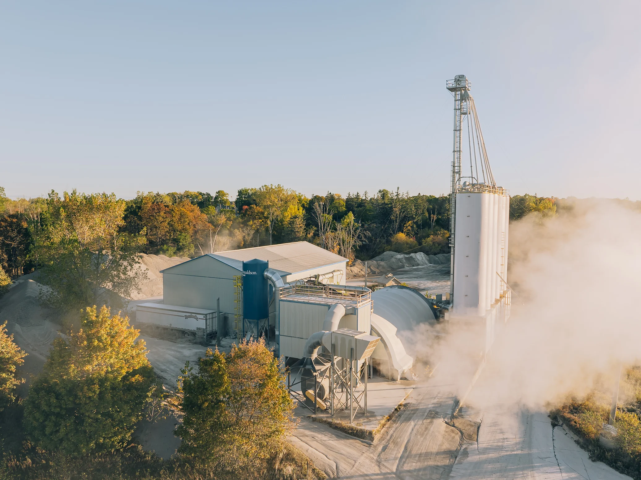 Type 1L Cement - cement plant buildings and a tall tower with steam drifting across in early morning light