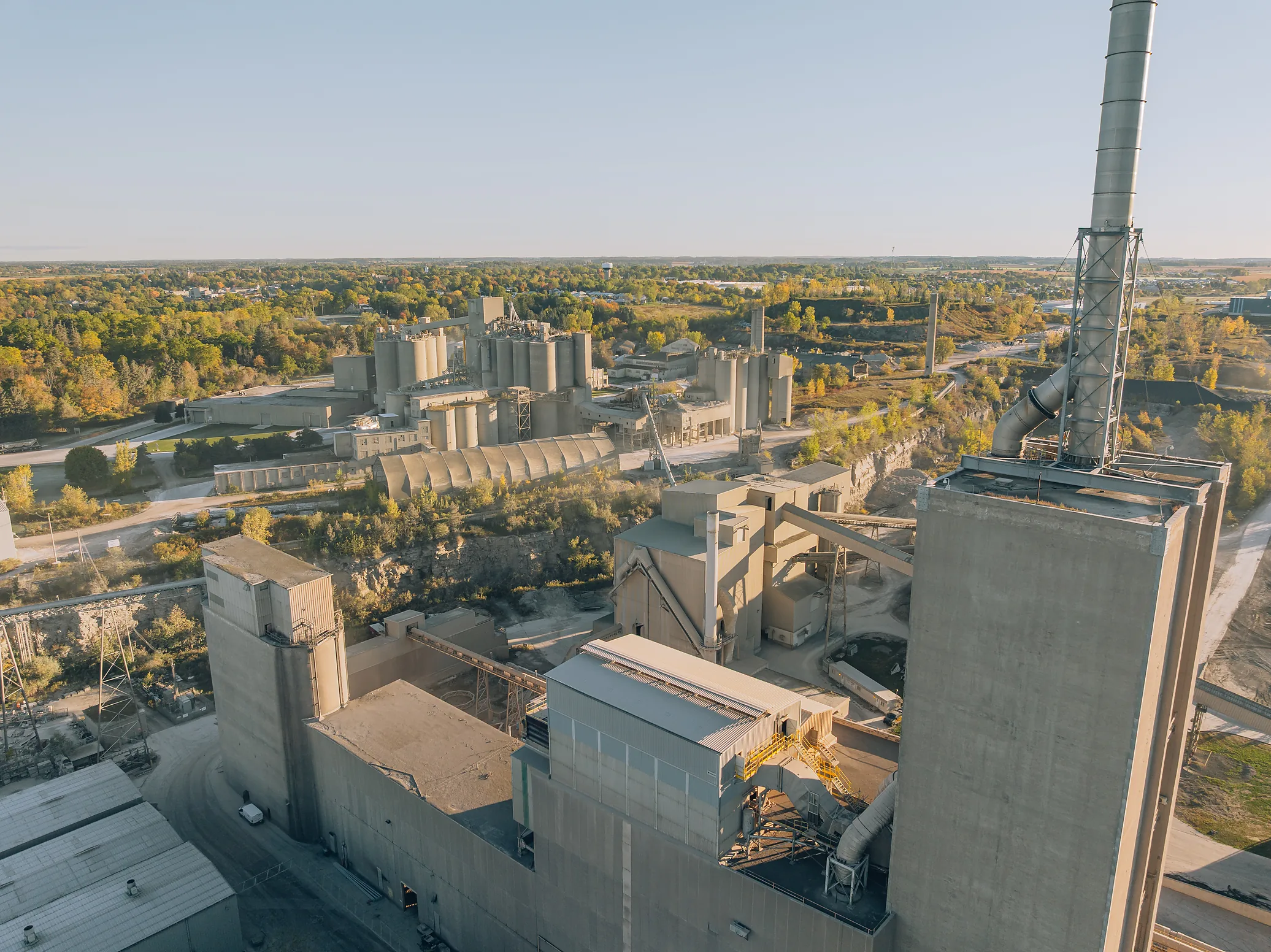 Cement Type IL(HE) - elevated view of cement plant buildings and stack with the town and trees beyond