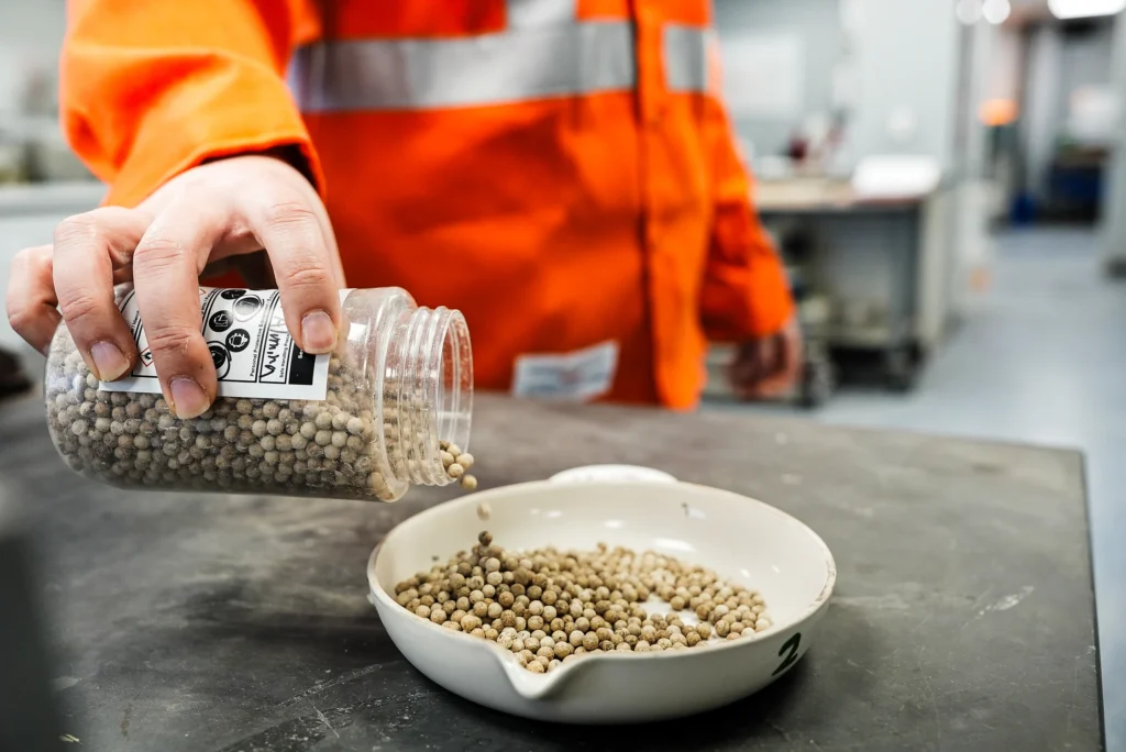 St Marys Community Relations - lab technician pouring pelletized material samples from a jar into a dish