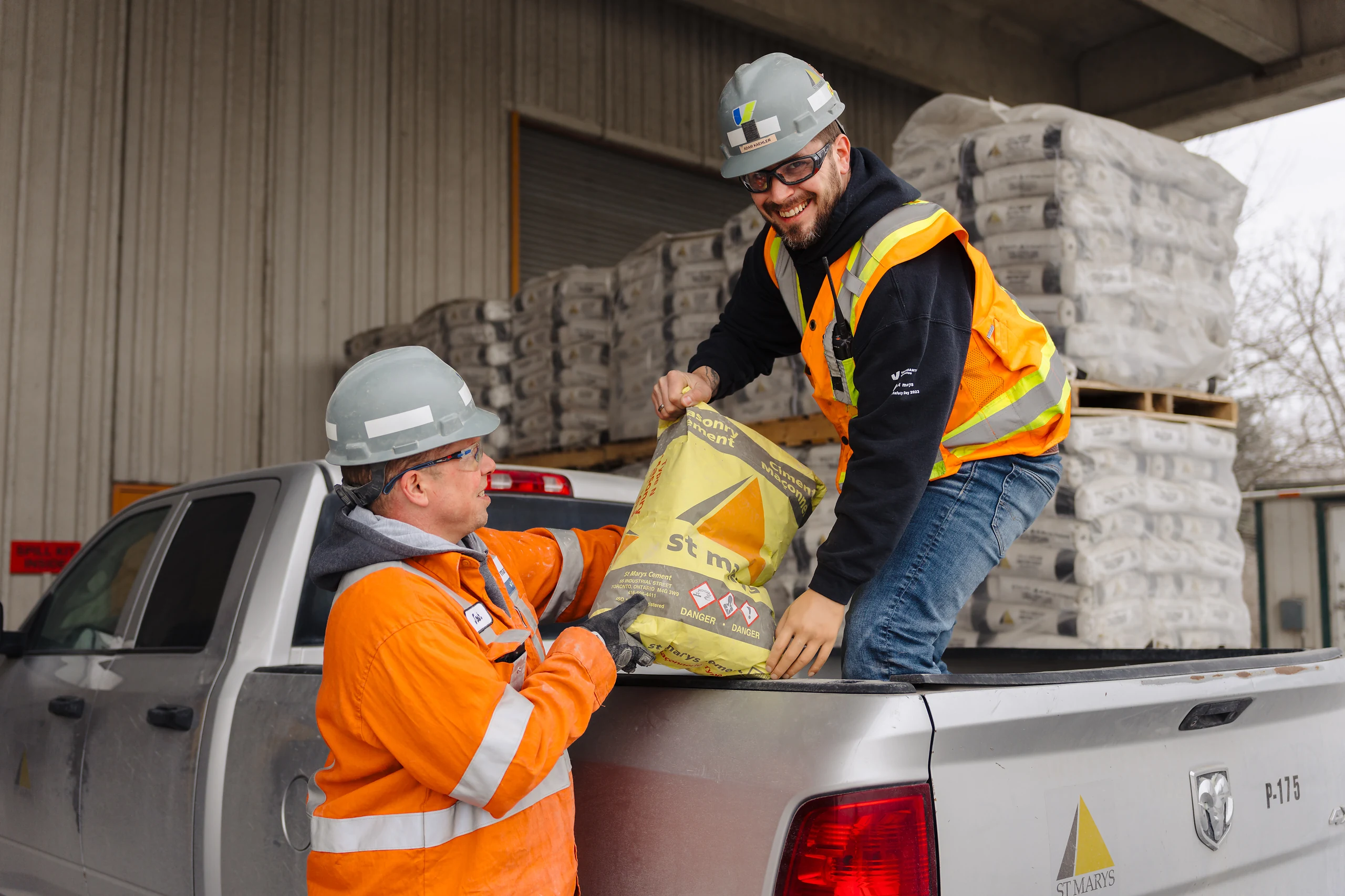 Cement Jobs - workers in hard hats loading bagged cement into a customer's pickup truck