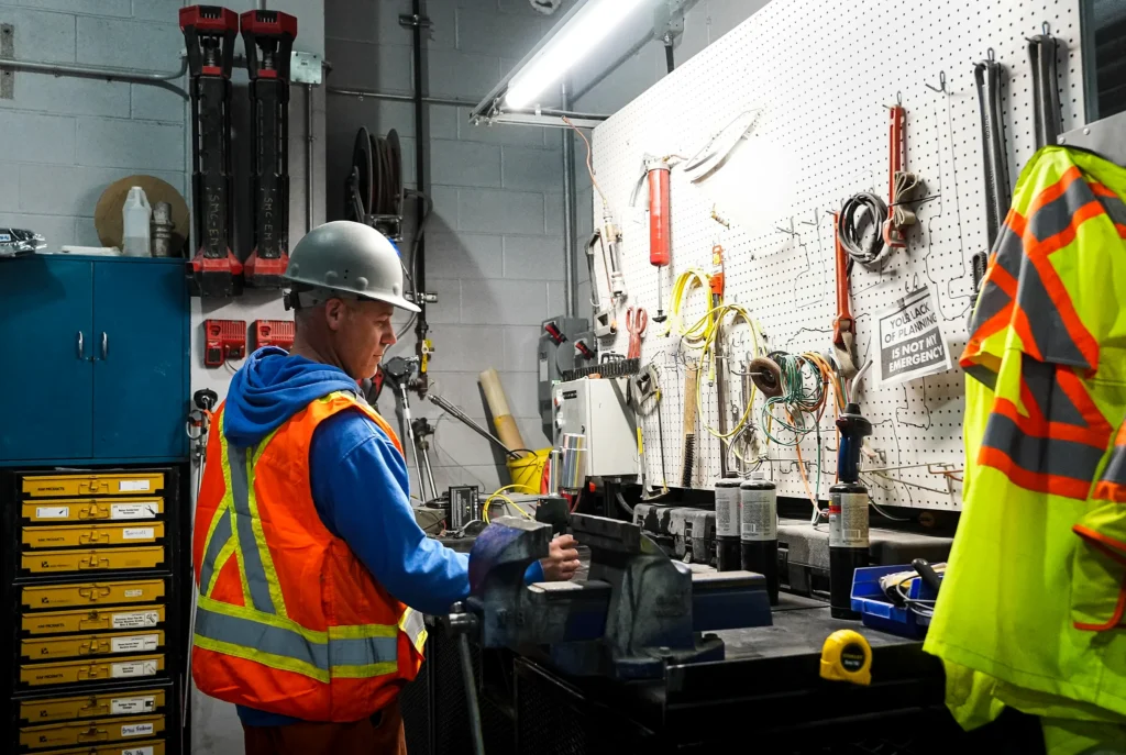 Detroit Cement Plant - maintenance worker in hi-vis at a workshop bench with tools on a pegboard wall